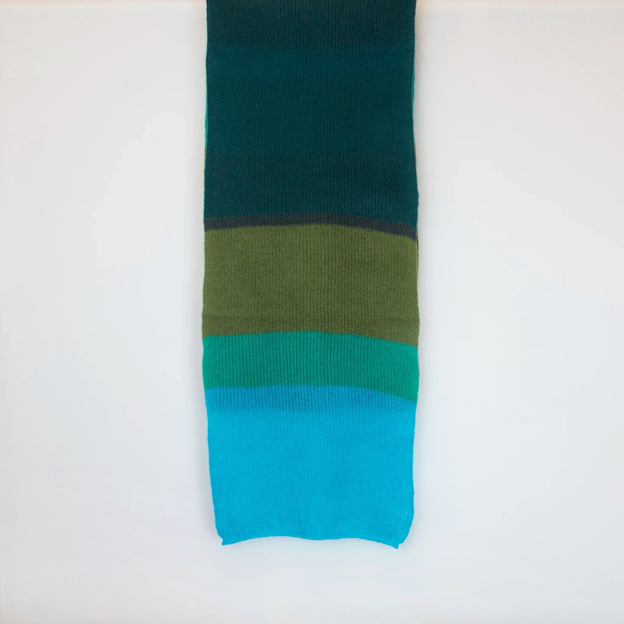 Sciarpa in lana mohair, verde,  Made in Italy, realizzata nel più antico lanificio della Calabria su telai degli anni '30, garantendo qualità e durata nel tempo. I colori ispirati al sottobosco autunnale dell'Appennino Silano evocano la quiete e la bellezza dei paesaggi autunnali. Morbida al tatto, offre una sensazione di sofficità che avvolge delicatamente il corpo, per un comfort senza pari.