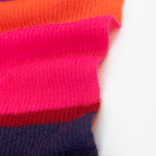 Dettaglio e texture tessuto della Sciarpa in lana mohair viola, fucsia, arancio, Made in Italy, realizzata nel più antico lanificio della Calabria su telai degli anni '30, garantendo qualità e durata nel tempo. I colori ispirati ai frutti rossi dei boschi evocano calore e naturale bellezza. Morbida al tatto, offre una sensazione di sofficità che avvolge delicatamente il corpo, per un comfort senza pari.