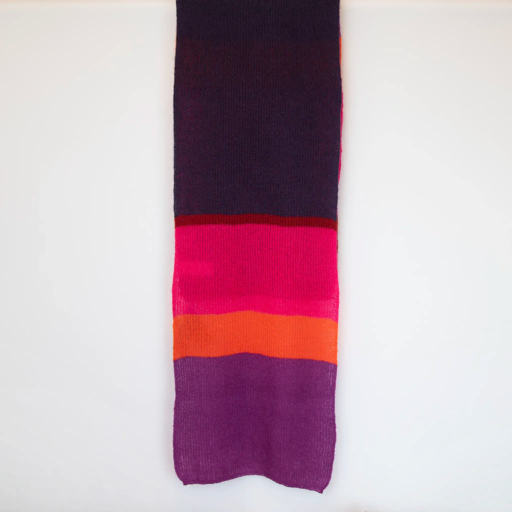 Sciarpa in lana mohair viola, fucsia, arancio, Made in Italy, realizzata nel più antico lanificio della Calabria su telai degli anni '30, garantendo qualità e durata nel tempo. I colori ispirati ai frutti rossi dei boschi evocano calore e naturale bellezza. Morbida al tatto, offre una sensazione di sofficità che avvolge delicatamente il corpo, per un comfort senza pari.