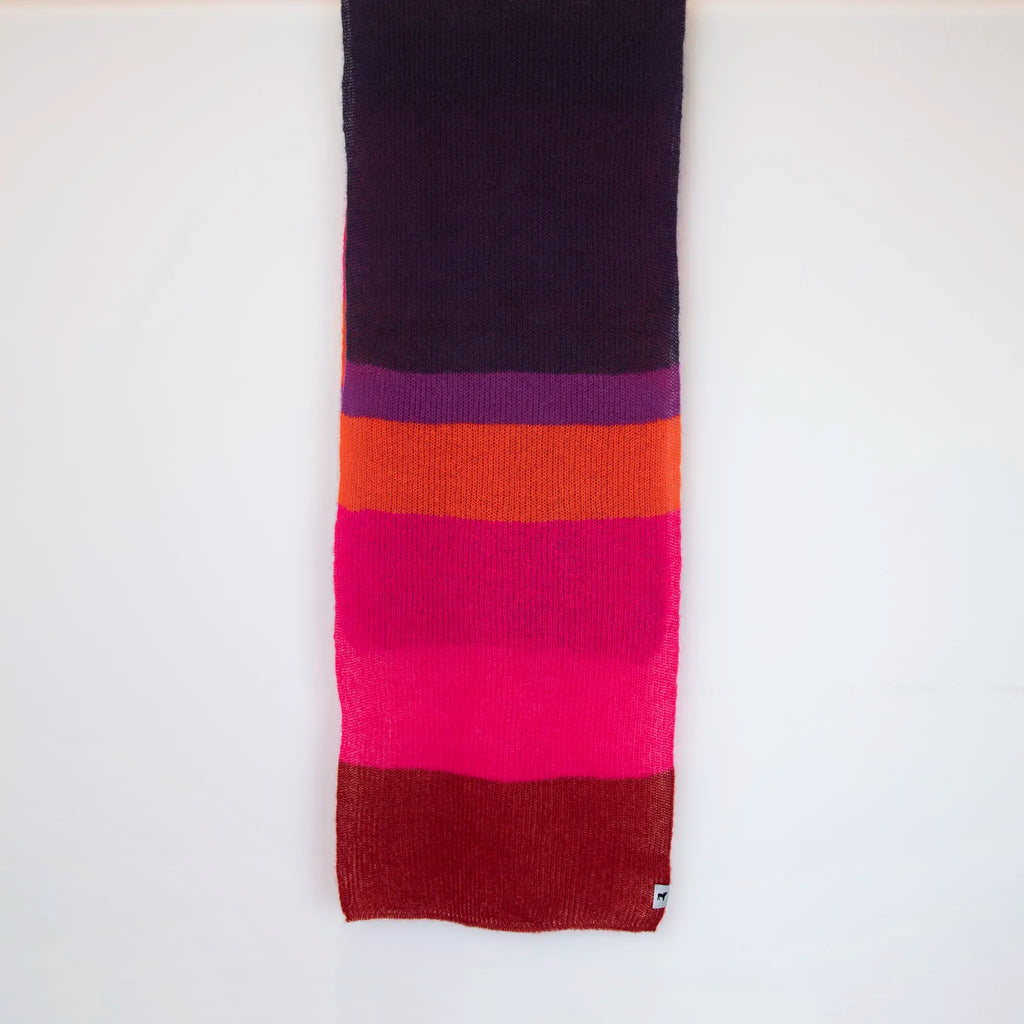 Sciarpa in lana mohair viola, fucsia, arancio, Made in Italy, realizzata nel più antico lanificio della Calabria su telai degli anni '30, garantendo qualità e durata nel tempo. I colori ispirati ai frutti rossi dei boschi evocano calore e naturale bellezza. Morbida al tatto, offre una sensazione di sofficità che avvolge delicatamente il corpo, per un comfort senza pari.
