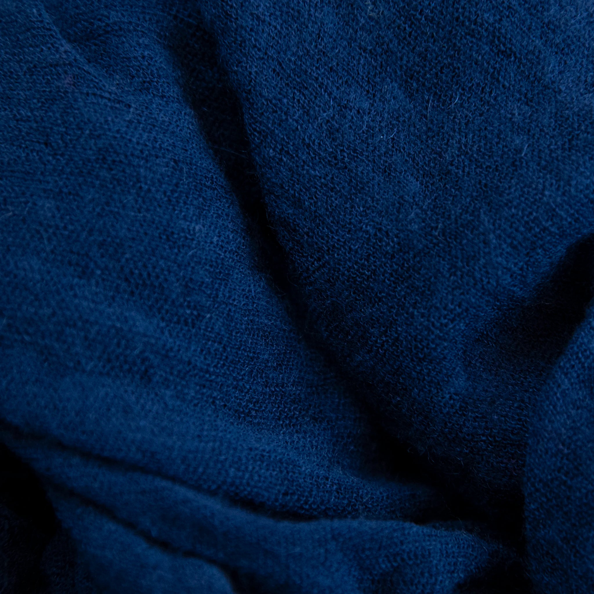 Dettagli e texture tessuto della pashmina blu in 100% cashmere Made in Italy, tessitura a jersey, leggera e vaporosa, perfetta come sciarpa o stola per tutte le stagioni.