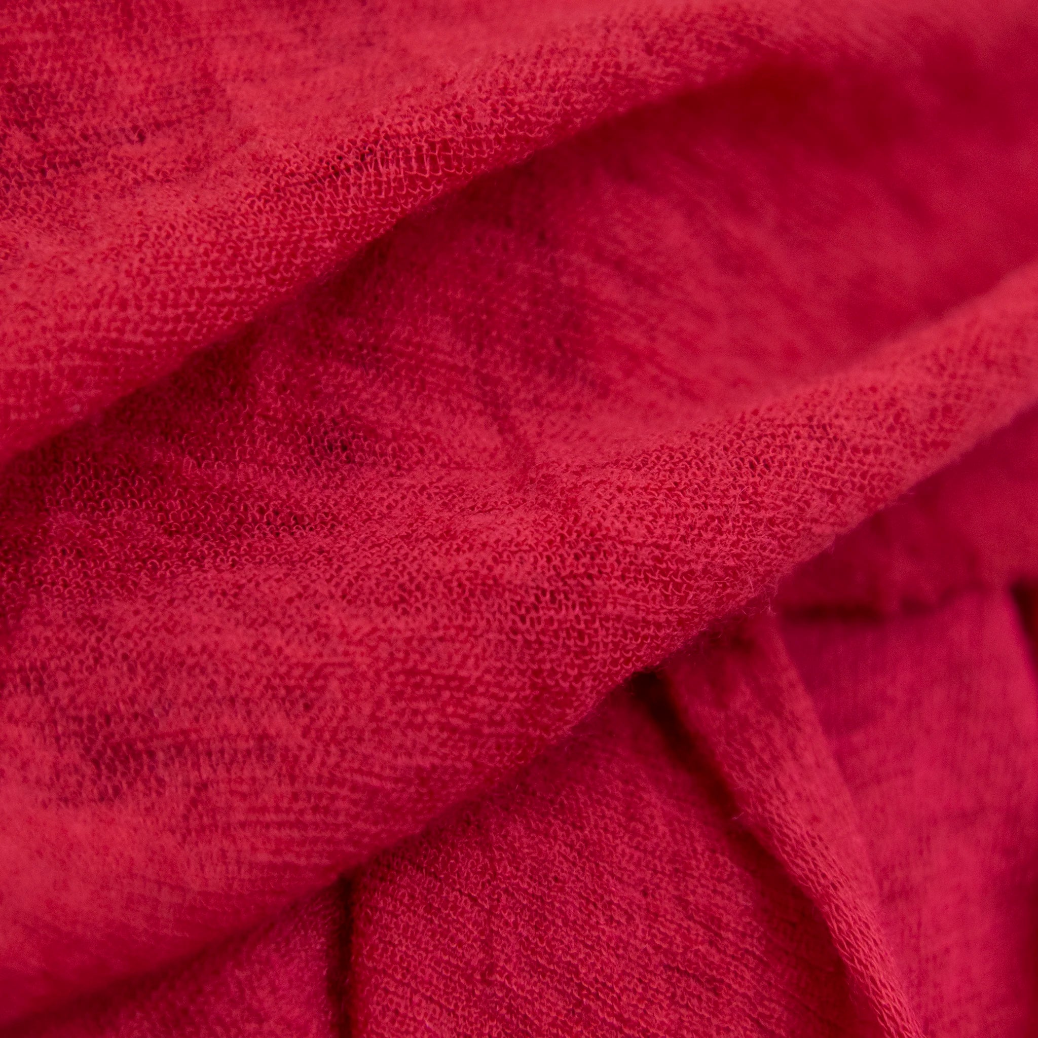 Dettagli e texture tessuto della pashmina rossa in 100% cashmere Made in Italy, tessitura a jersey, leggera e vaporosa, perfetta come sciarpa o stola per tutte le stagioni.