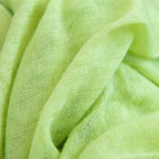 Dettagli e texture tessuto della pashmina verde in 100% cashmere Made in Italy, tessitura a jersey, leggera e vaporosa, perfetta come sciarpa o stola per tutte le stagioni.