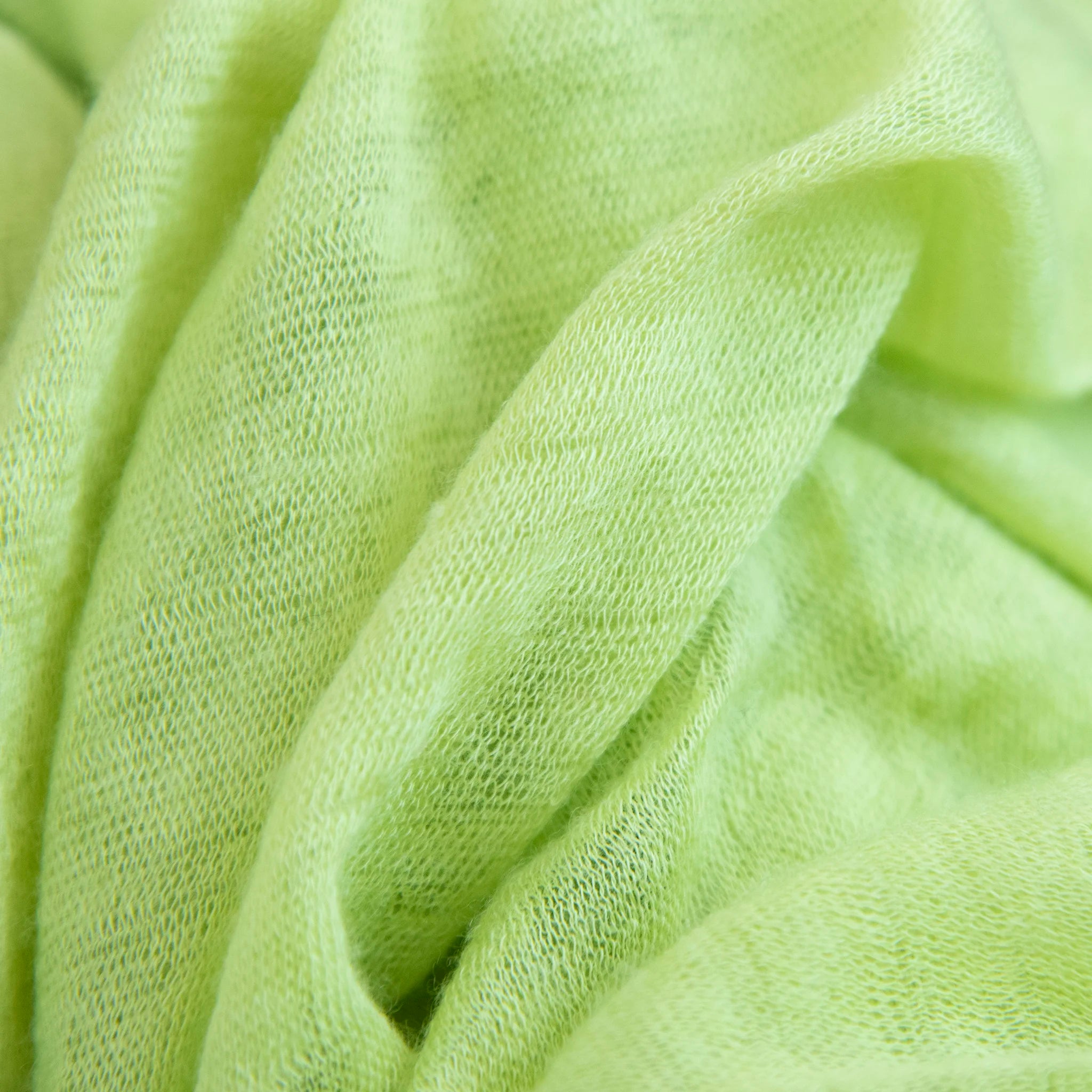 Dettagli e texture tessuto della pashmina verde in 100% cashmere Made in Italy, tessitura a jersey, leggera e vaporosa, perfetta come sciarpa o stola per tutte le stagioni.