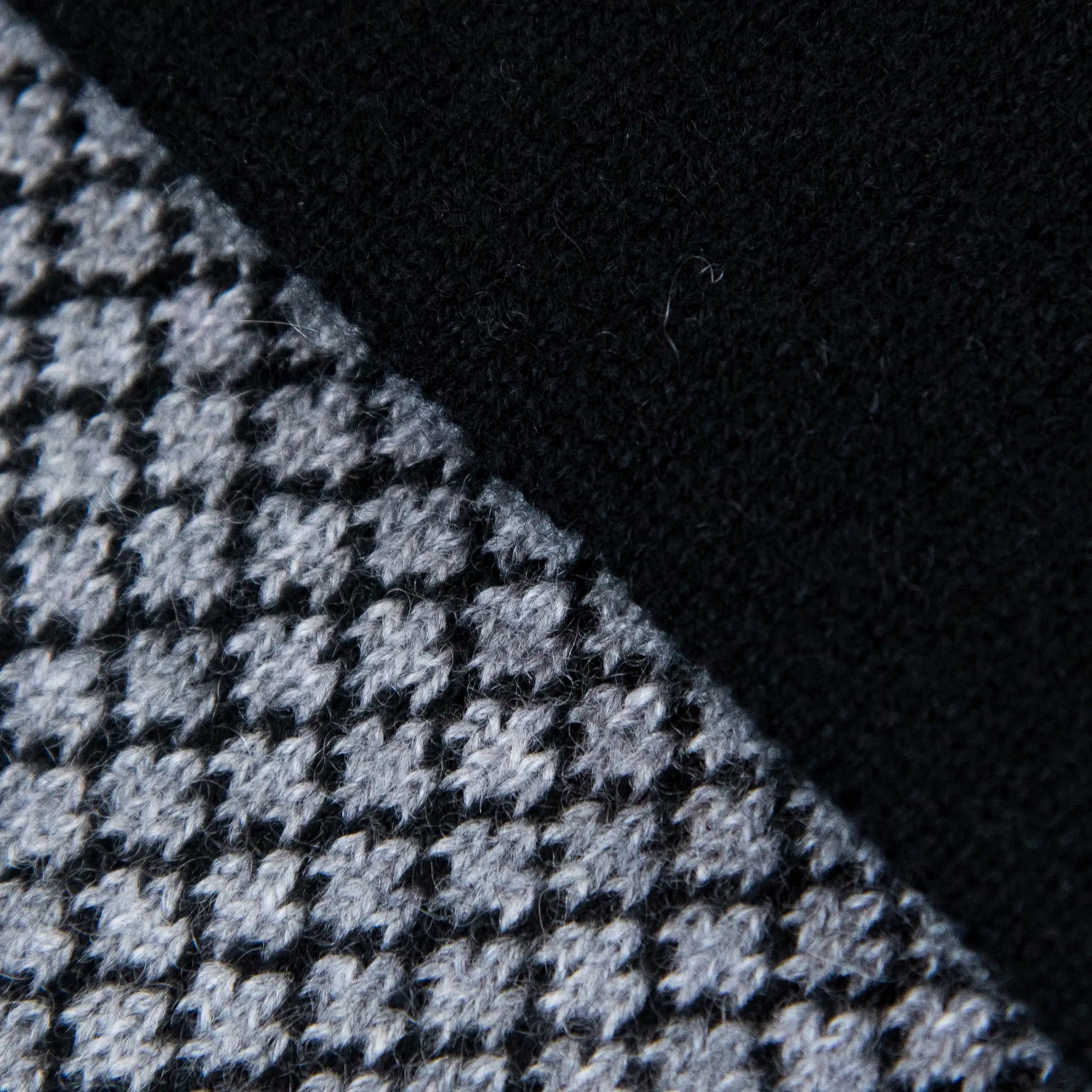Dettagli e texture tessuto della sciarpa scaldacollo Jacquard double-face nera e grigia con asola in 100% Cashmere beige. Morbida, versatile e facile da indossare.