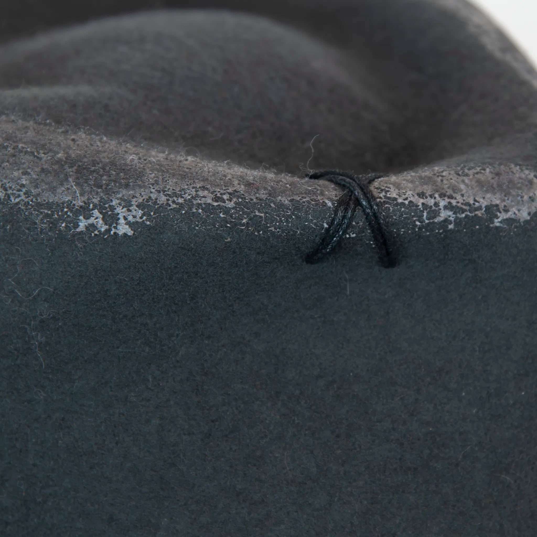 Dettaglio e tessuto del cappello Racket in feltro di lana grigio, Made in Italy, realizzato a mano con antiche forme in legno. Cuciture e dettagli di invecchiamento artigianali per un look unico.