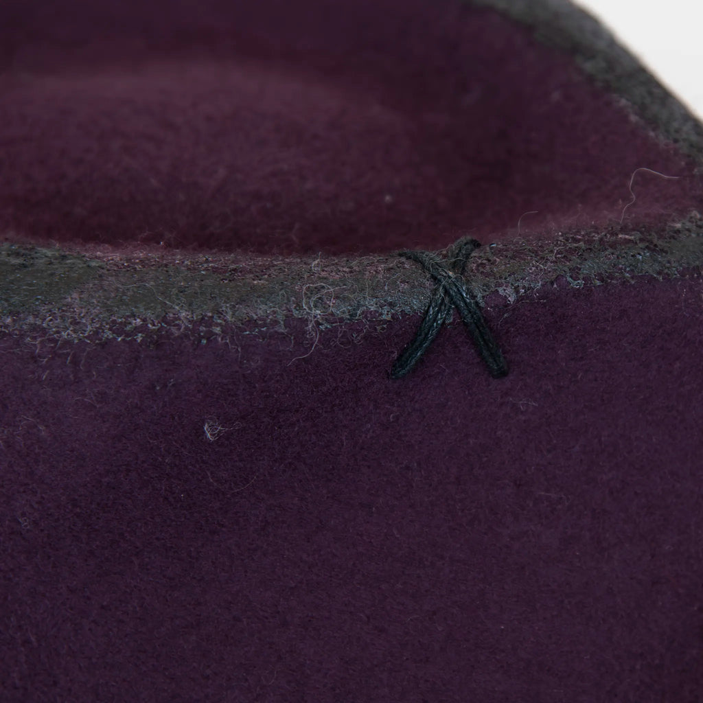 Dettaglio e tessuto del cappello Racket in feltro di lana viola, Made in Italy, realizzato a mano con antiche forme in legno. Cuciture e dettagli di invecchiamento artigianali per un look unico.