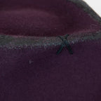 Dettaglio e tessuto del cappello Racket in feltro di lana viola, Made in Italy, realizzato a mano con antiche forme in legno. Cuciture e dettagli di invecchiamento artigianali per un look unico.