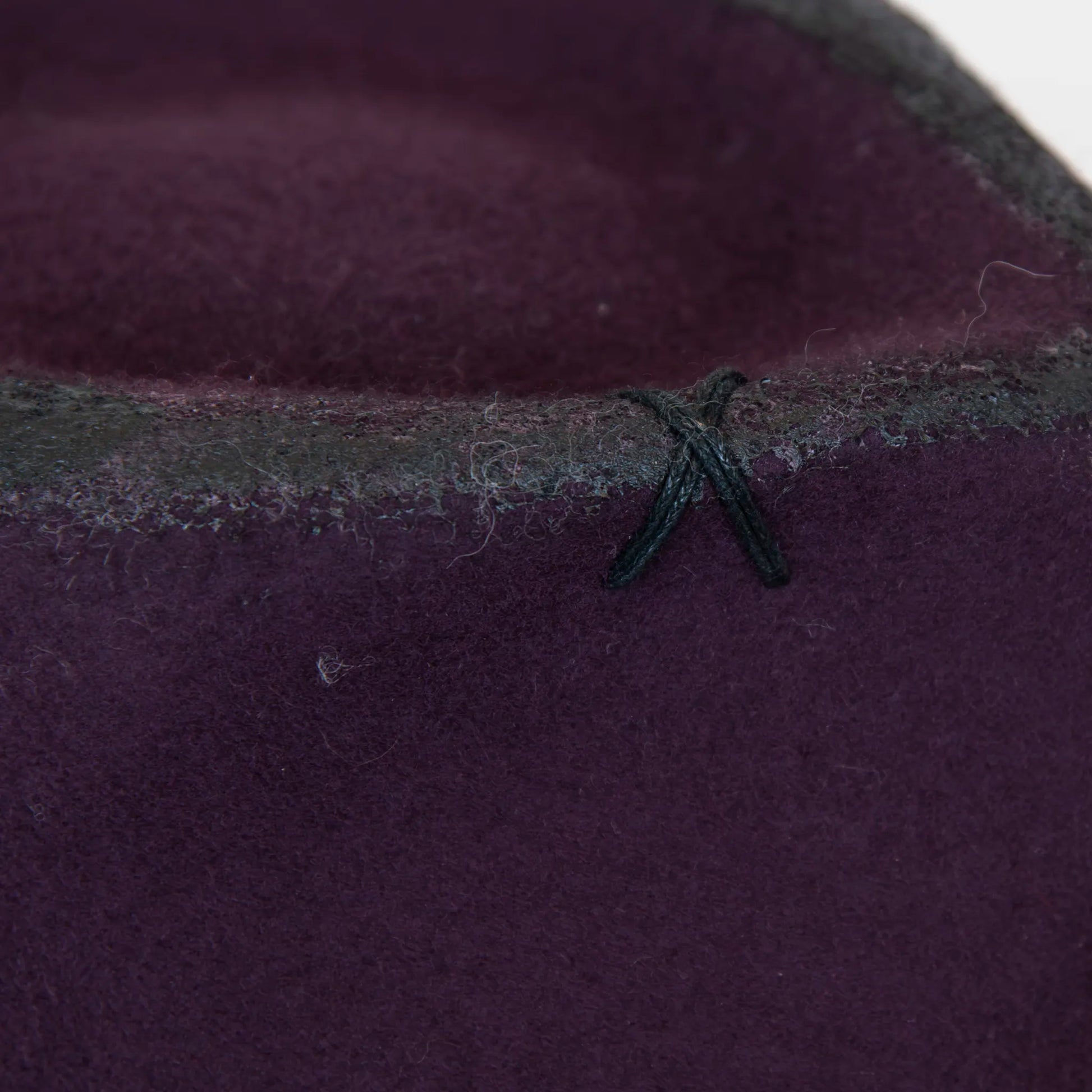 Dettaglio e tessuto del cappello Racket in feltro di lana viola, Made in Italy, realizzato a mano con antiche forme in legno. Cuciture e dettagli di invecchiamento artigianali per un look unico.