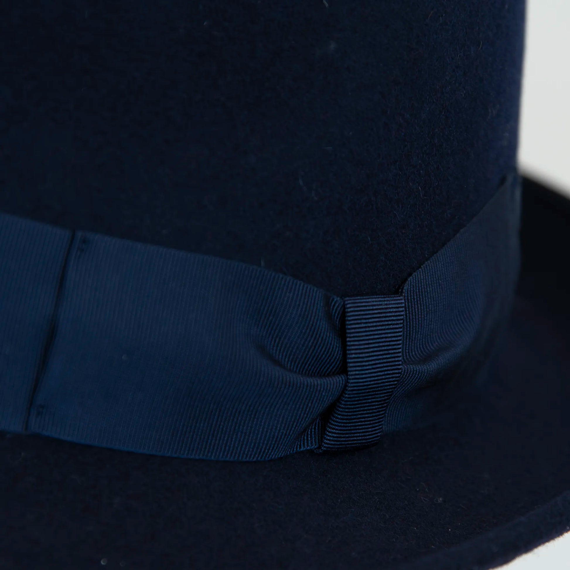 Dettaglio cinta e tessuto del cappello in feltro di lana blu, Made in Italy, ispirato a Humphrey Bogart. Falda media 5,5 cm rialzata sul retro, cupola 11,5 cm, cinta in gros-grain 4 cm blu. Eleganza senza tempo.