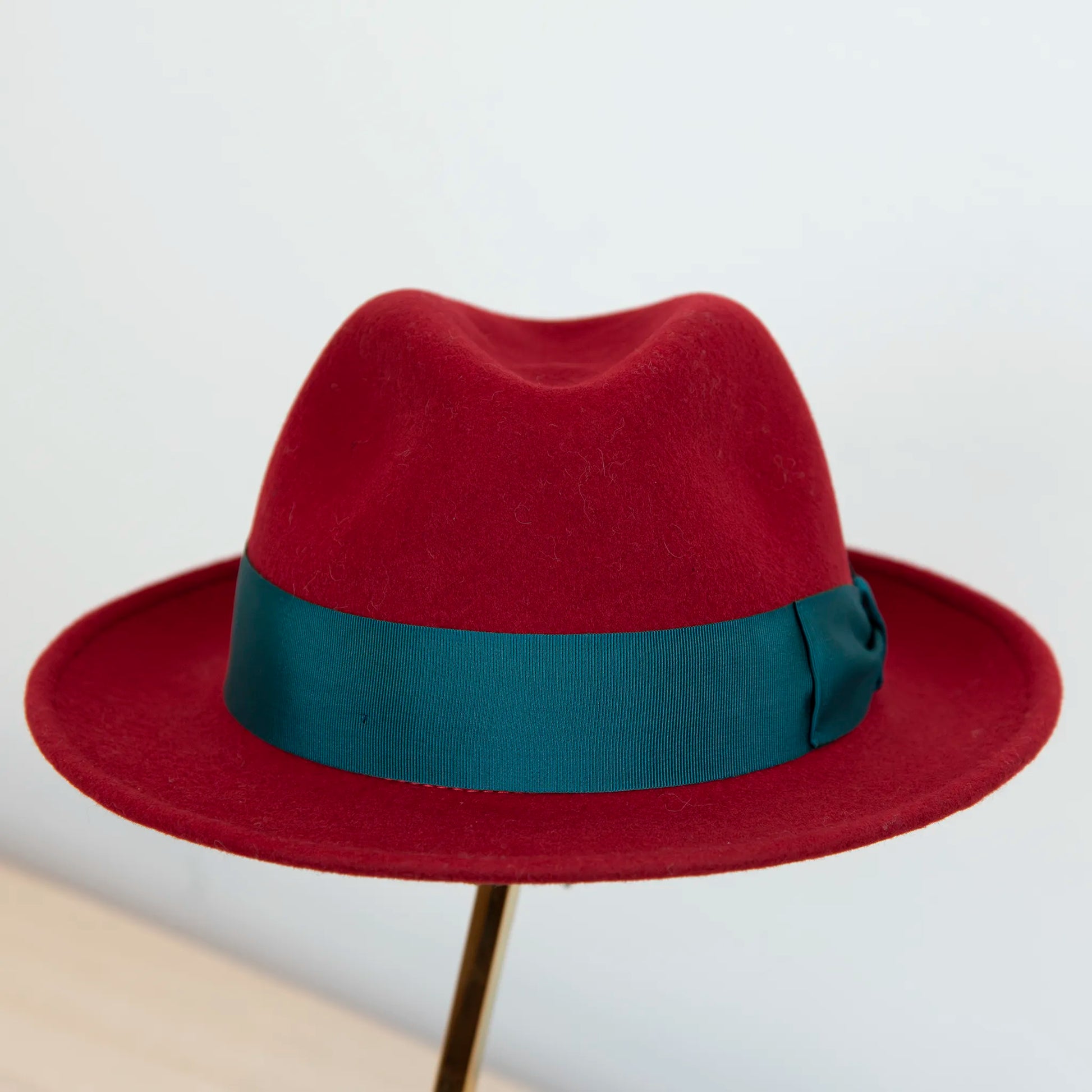 Cappello in feltro di lana rosso, Made in Italy, ispirato a Humphrey Bogart. Falda media 5,5 cm rialzata sul retro, cupola 11,5 cm, cinta in gros-grain 4 cm verde. Eleganza senza tempo.