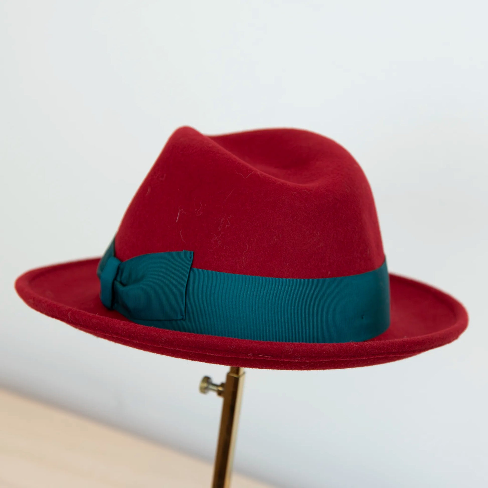 Cappello in feltro di lana rosso, Made in Italy, ispirato a Humphrey Bogart. Falda media 5,5 cm rialzata sul retro, cupola 11,5 cm, cinta in gros-grain 4 cm verde. Eleganza senza tempo.