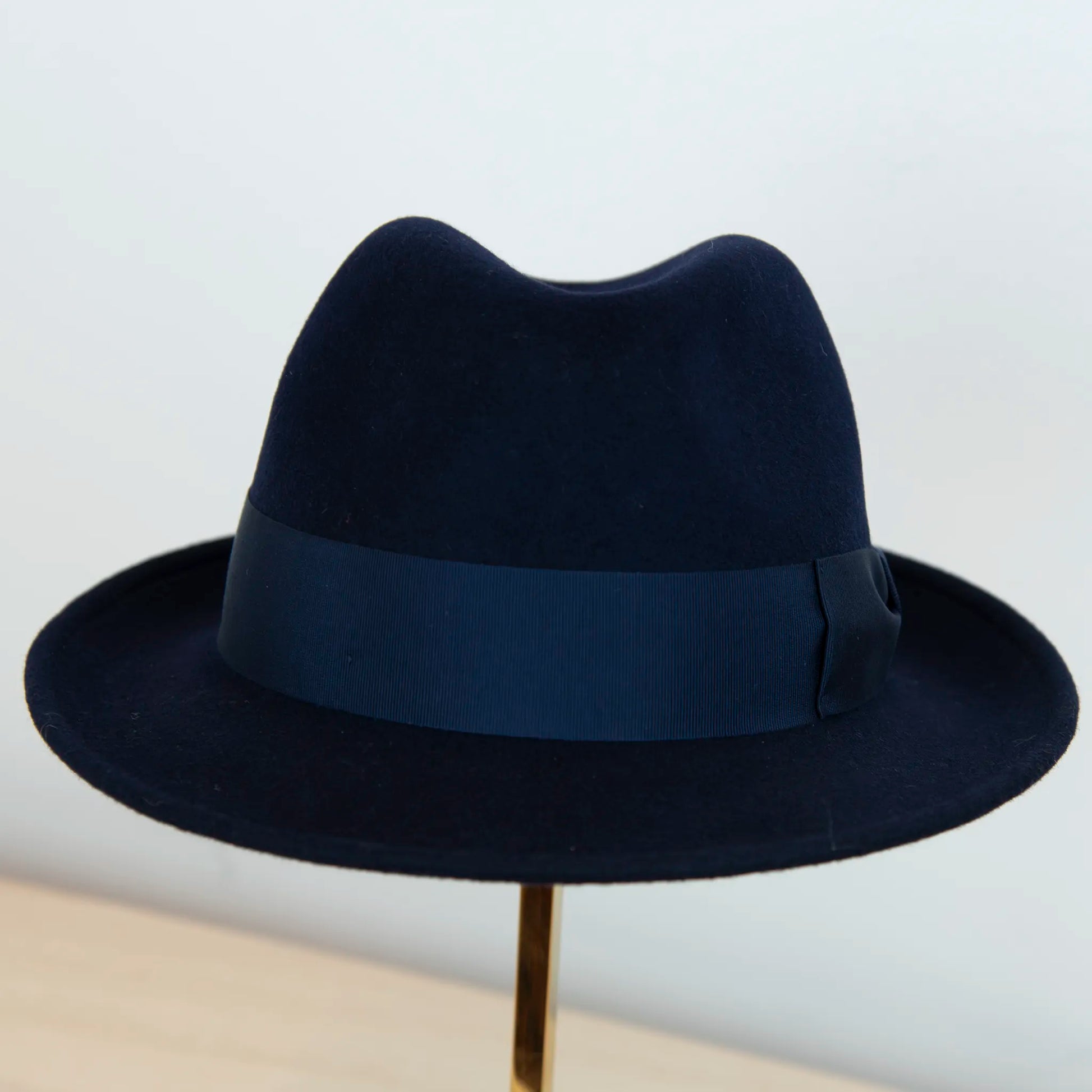 Dettaglio del cappello in feltro di lana blu, Made in Italy, ispirato a Humphrey Bogart. Falda media 5,5 cm rialzata sul retro, cupola 11,5 cm, cinta in gros-grain 4 cm blu. Eleganza senza tempo.