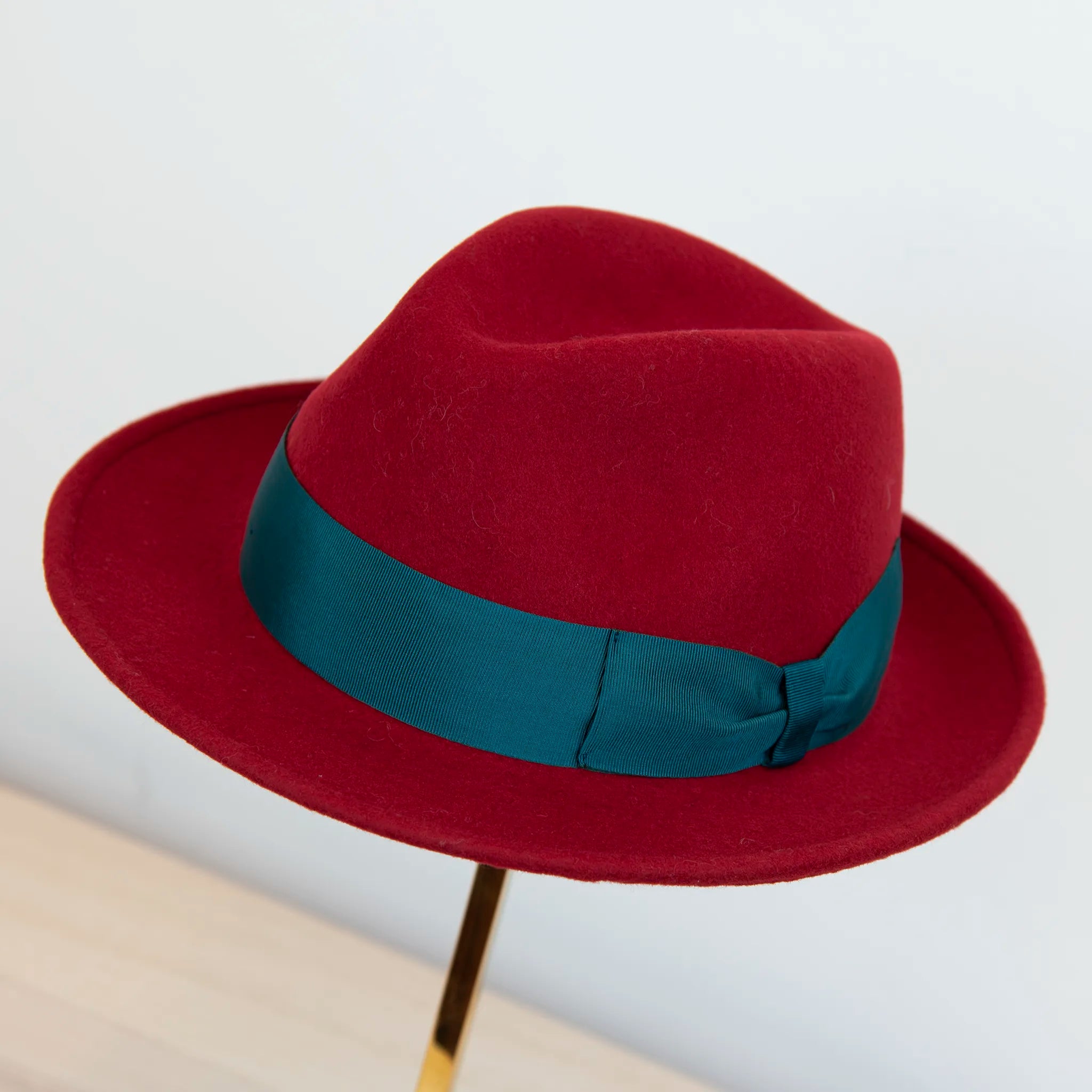 Cappello in feltro di lana rosso, Made in Italy, ispirato a Humphrey Bogart. Falda media 5,5 cm rialzata sul retro, cupola 11,5 cm, cinta in gros-grain 4 cm verde. Eleganza senza tempo.