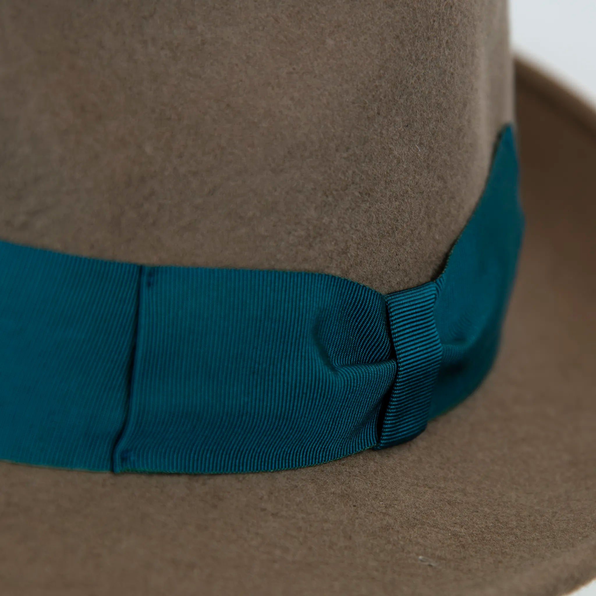 Dettaglio cinta e tessuto del Cappello in feltro di lana marrone Made in Italy, ispirato a Humphrey Bogart. Falda media 5,5 cm rialzata sul retro, cupola 11,5 cm, cinta in gros-grain 4 cm verde. Eleganza senza tempo.