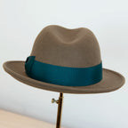 Cappello in feltro di lana marrone Made in Italy, ispirato a Humphrey Bogart. Falda media 5,5 cm rialzata sul retro, cupola 11,5 cm, cinta in gros-grain 4 cm verde. Eleganza senza tempo.