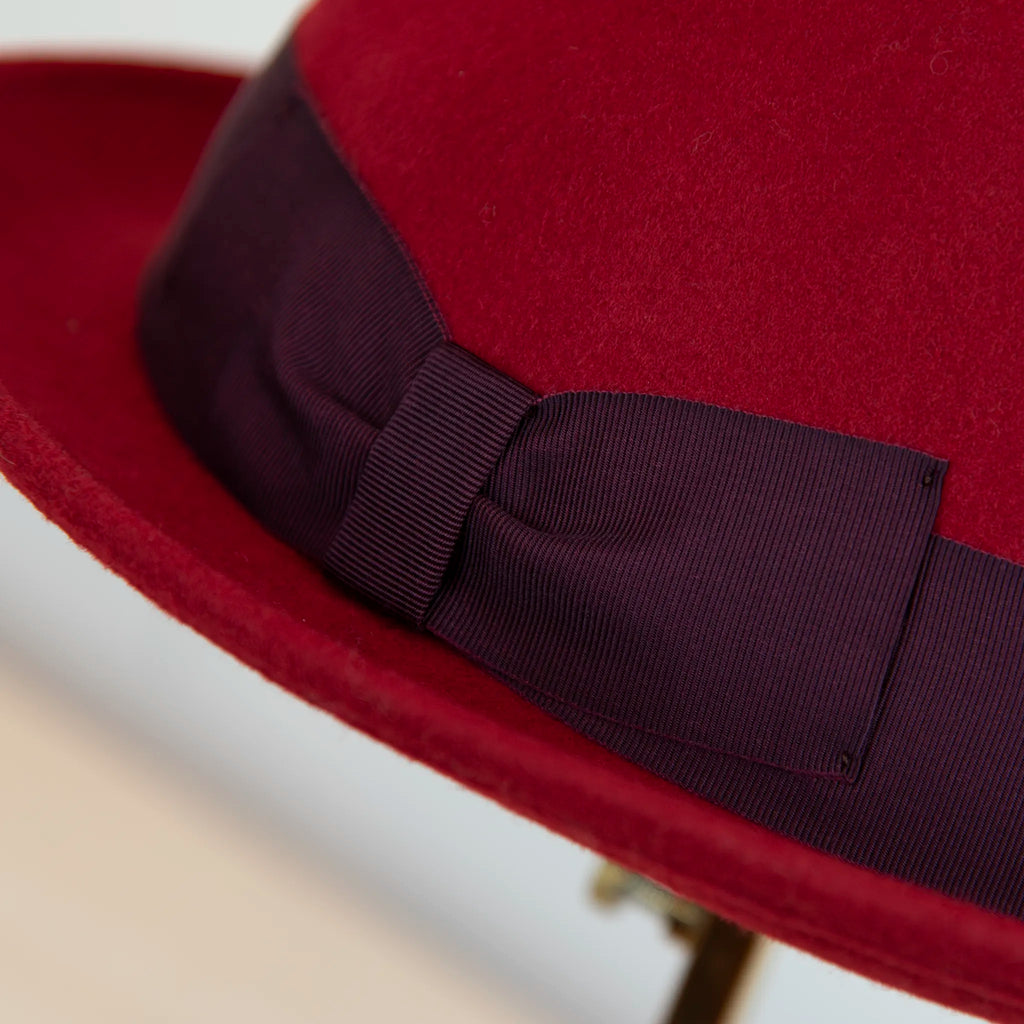 Dettaglio cinta e tessuto del cappello in feltro di lana Rosso, Made in Italy, falda corta 5 cm e cinta in gros-grain viola. Parte della Collezione Emporio San Felice, elegante e versatile per ogni occasione.
