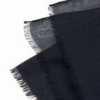 Dettagli e texture della Pashmina in 100% cashmere nera a tessitura twill, pregiata manifattura Made in Italy, sottile ed elegante adatta a ogni stagione.