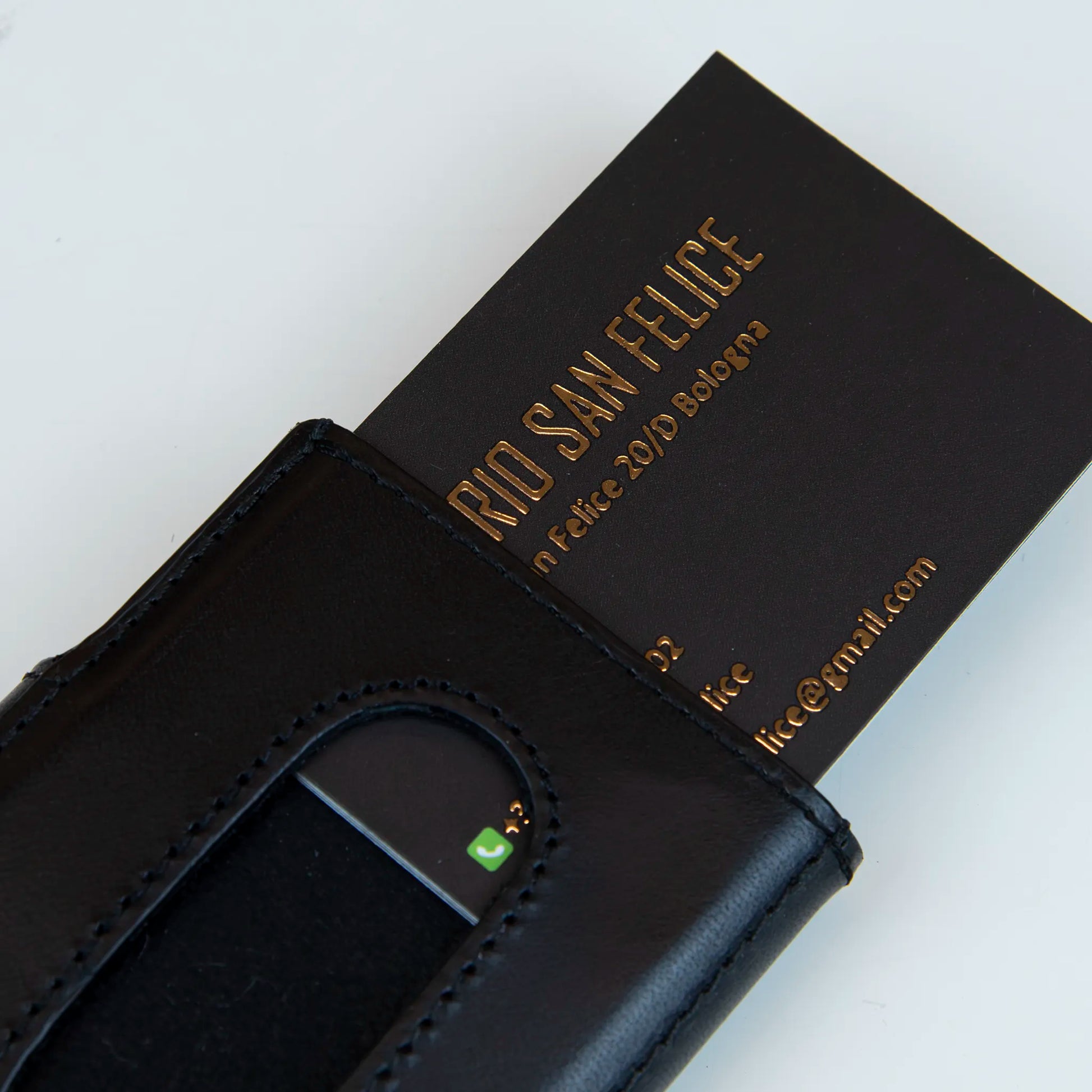 Portafoglio compatto in pelle nero, Made in Italy, artigianale, con due scomparti scorrevoli per 5/6 carte ciascuno, molla porta banconote e scomparto per monete.