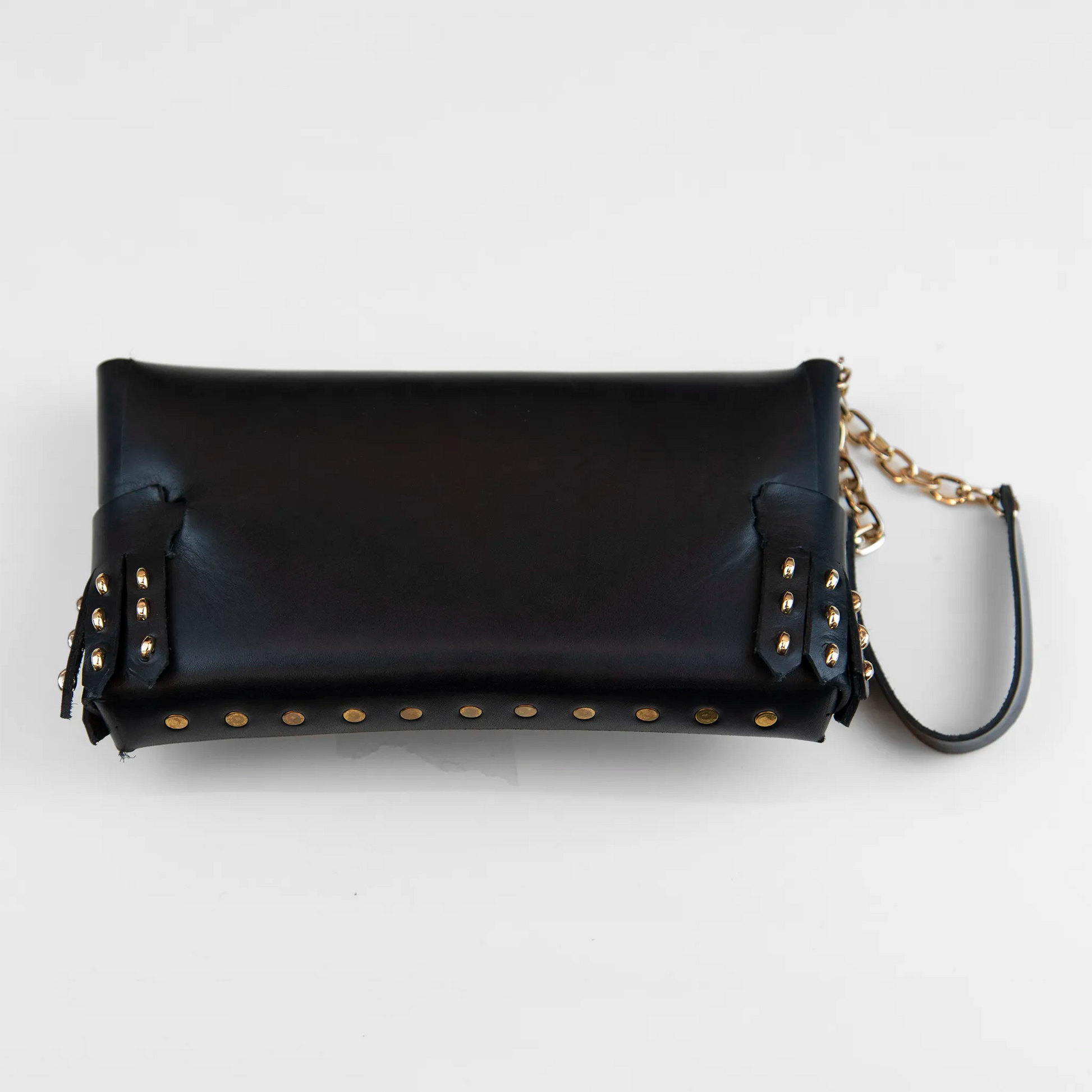 Portatutto in pelle nero borchiato con chiusura a calamita e polsiera per facile trasporto. Made in Italy, realizzato senza cuciture, secondo la tradizione degli antichi sellai Toscani, per maggiore robustezza e durata.