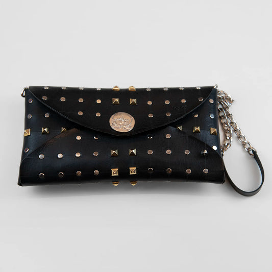 Clutch in pelle nera borchiata con chiusura a calamita, polsiera e tracolla, Made in Italy, realizzata interamente a mano senza cuciture, secondo la tradizione degli antichi sellai Toscani, per garantire robustezza e durata nel tempo.