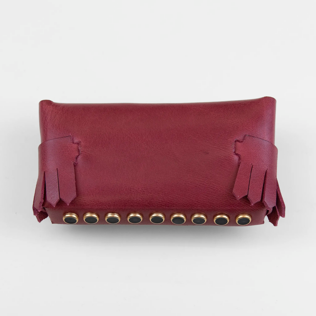 Portatutto in pelle rosso borchiato con chiusura a calamita, Made in Italy, realizzato interamente a mano senza cuciture secondo la tradizione degli antichi sellai Toscani, per una maggiore robustezza e durata nel tempo.
