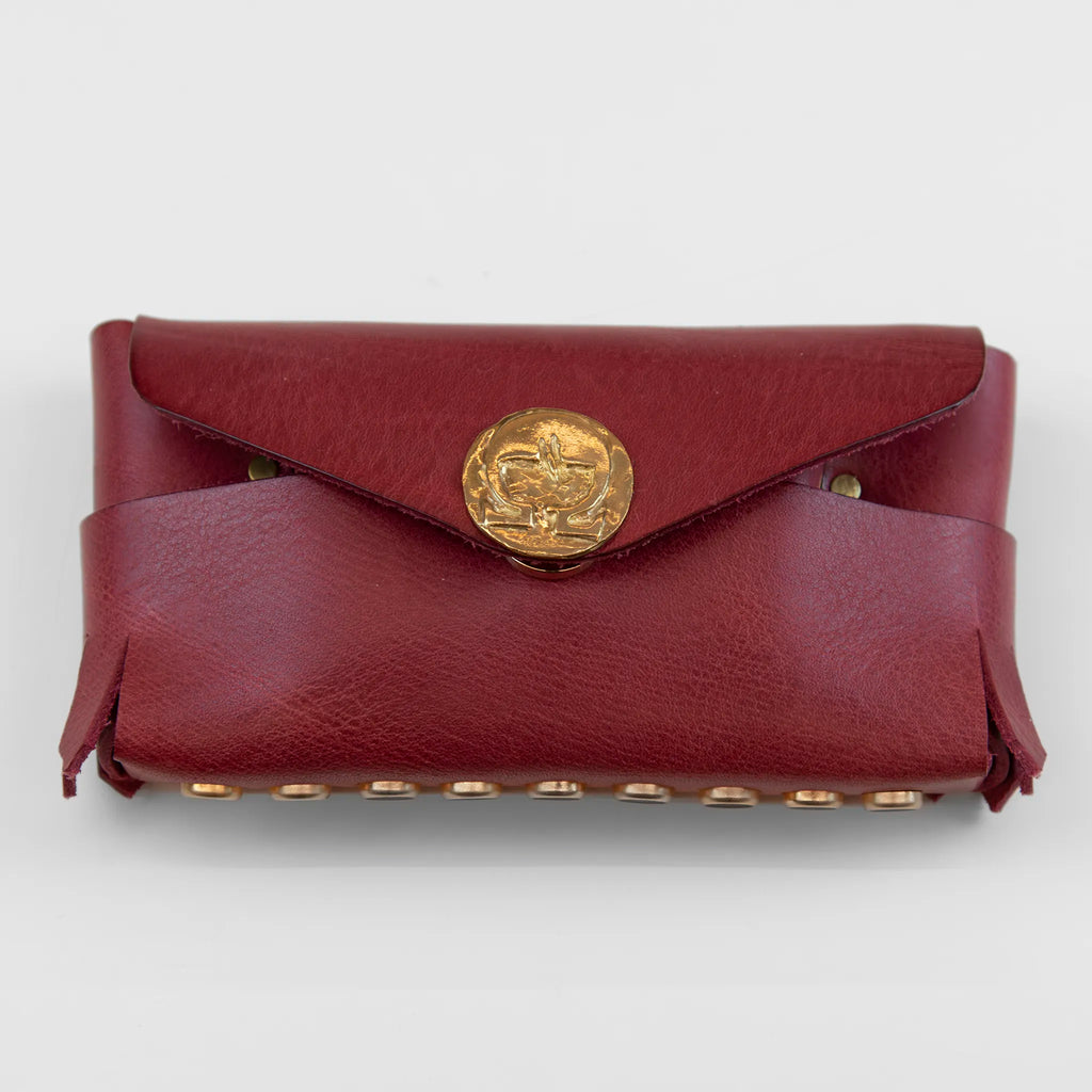 Portatutto in pelle rosso borchiato con chiusura a calamita, Made in Italy, realizzato interamente a mano senza cuciture secondo la tradizione degli antichi sellai Toscani, per una maggiore robustezza e durata nel tempo.
