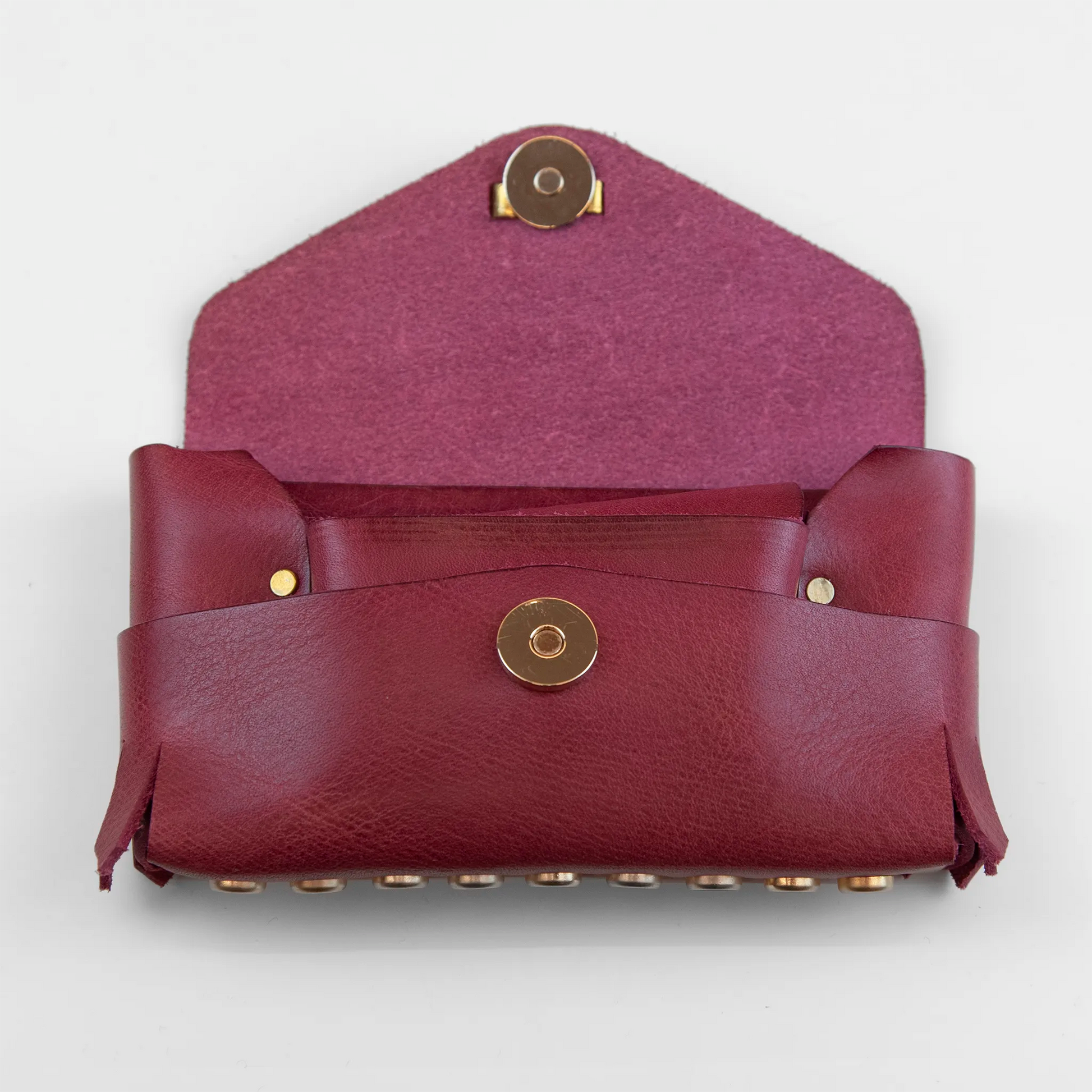 Portatutto in pelle rosso borchiato con chiusura a calamita, Made in Italy, realizzato interamente a mano senza cuciture secondo la tradizione degli antichi sellai Toscani, per una maggiore robustezza e durata nel tempo.
