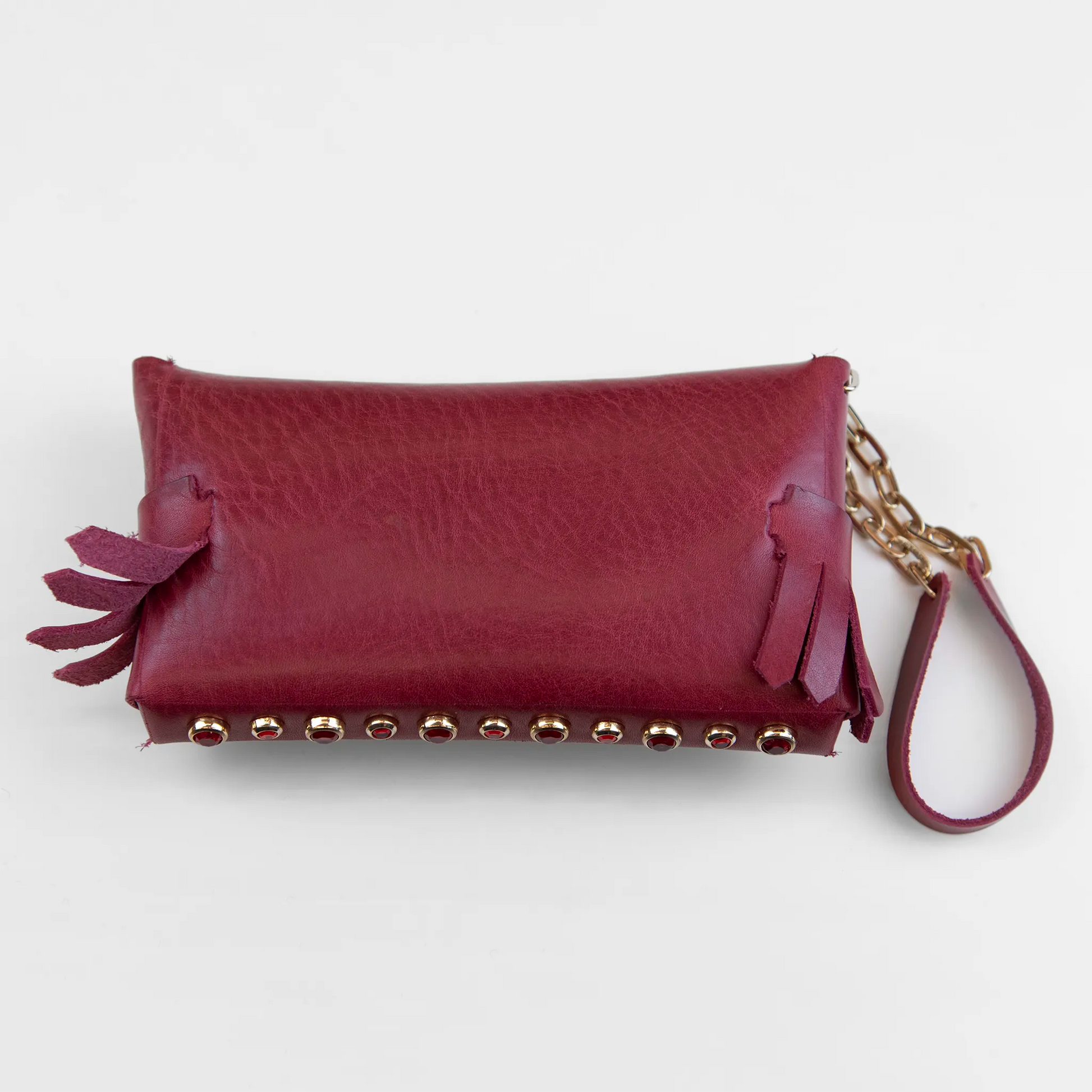 Portatutto in pelle rosso borchiato con pietre colorate, chiusura a calamita e polsiera per un pratico trasporto. Made in Italy, realizzato interamente a mano senza cuciture secondo la tradizione degli antichi sellai Toscani, per maggiore robustezza e durata nel tempo.