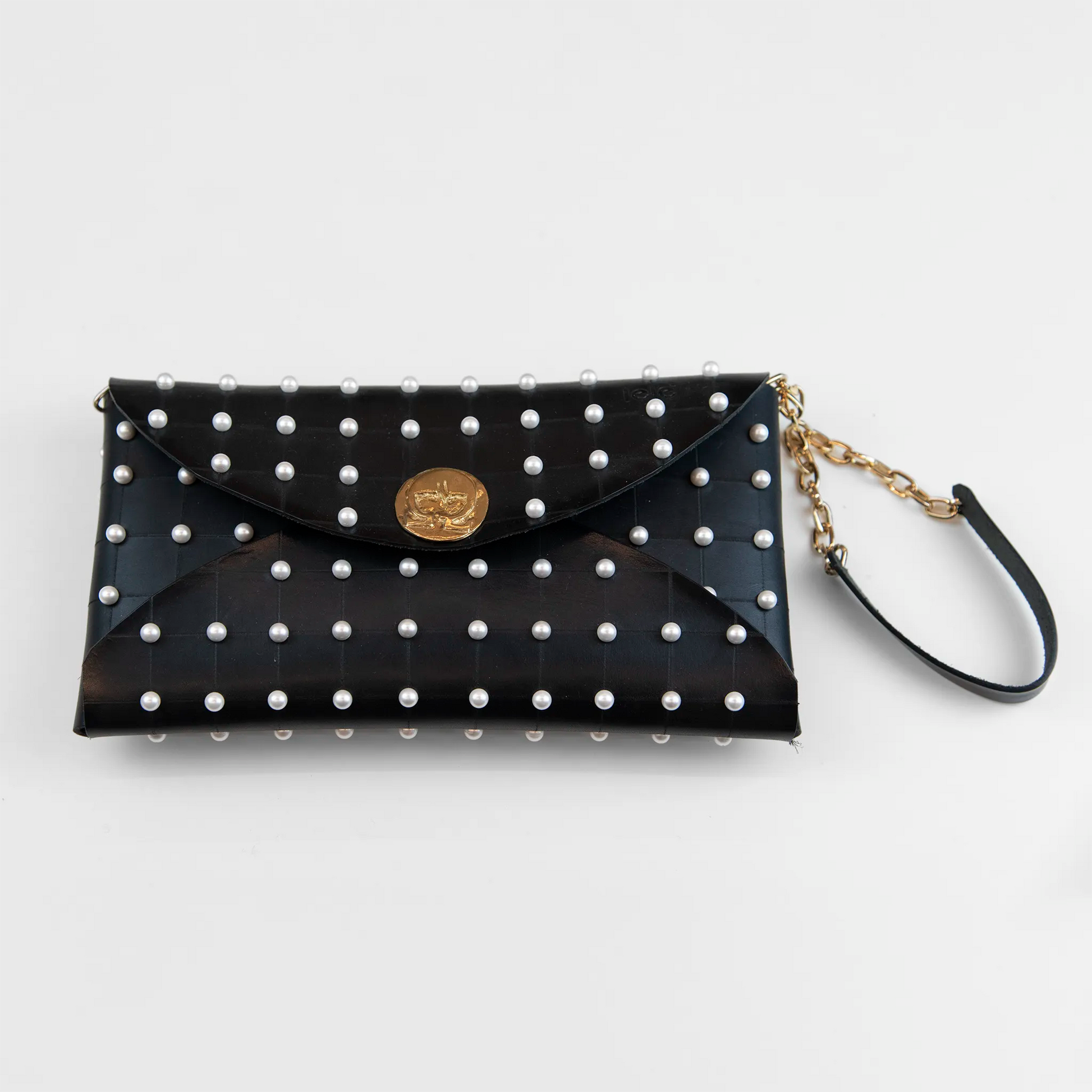 Clutch in pelle nera borchiata con chiusura a calamita, polsiera e tracolla per un pratico trasporto, Made in Italy, realizzata interamente a mano senza cuciture, secondo la tradizione degli antichi sellai Toscani, per robustezza e durata.