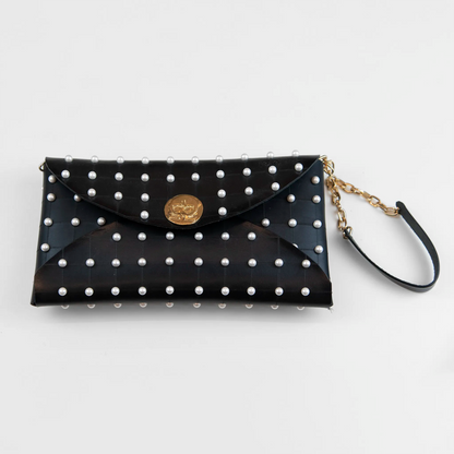 Clutch in pelle nera borchiata con chiusura a calamita, polsiera e tracolla per un pratico trasporto, Made in Italy, realizzata interamente a mano senza cuciture, secondo la tradizione degli antichi sellai Toscani, per robustezza e durata.