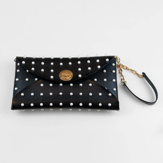 Clutch in pelle nera borchiata con chiusura a calamita, polsiera e tracolla per un pratico trasporto, Made in Italy, realizzata interamente a mano senza cuciture, secondo la tradizione degli antichi sellai Toscani, per robustezza e durata.