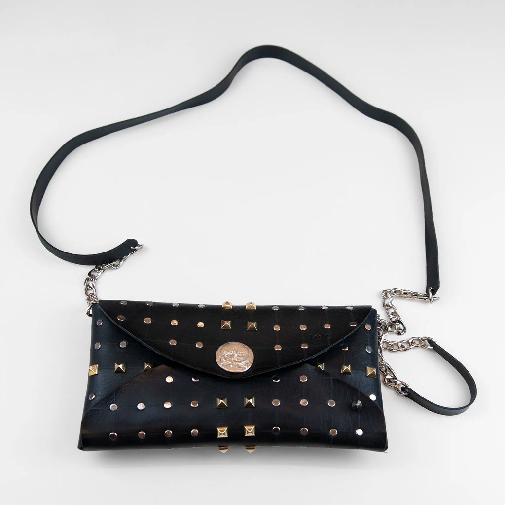 Clutch in pelle nera borchiata con chiusura a calamita, polsiera e tracolla, Made in Italy, realizzata interamente a mano senza cuciture, secondo la tradizione degli antichi sellai Toscani, per garantire robustezza e durata nel tempo.