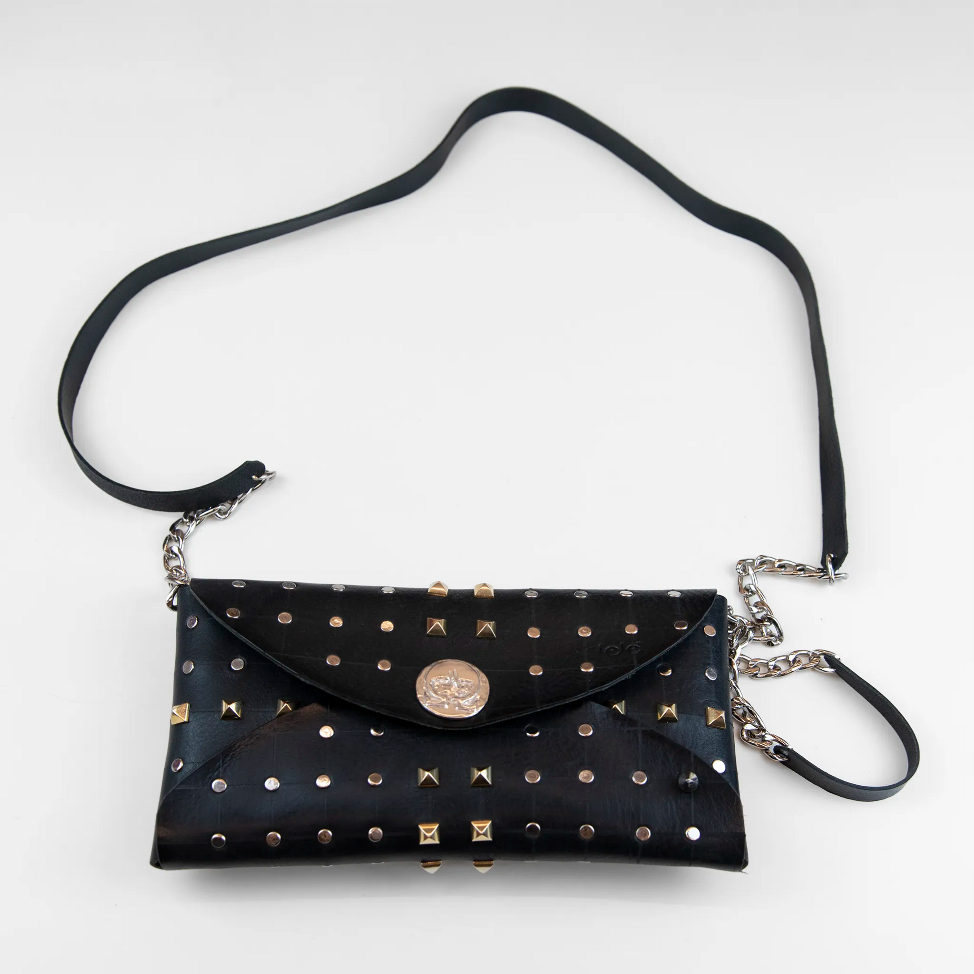Clutch in pelle nera borchiata con chiusura a calamita, polsiera e tracolla, Made in Italy, realizzata interamente a mano senza cuciture, secondo la tradizione degli antichi sellai Toscani, per garantire robustezza e durata nel tempo.