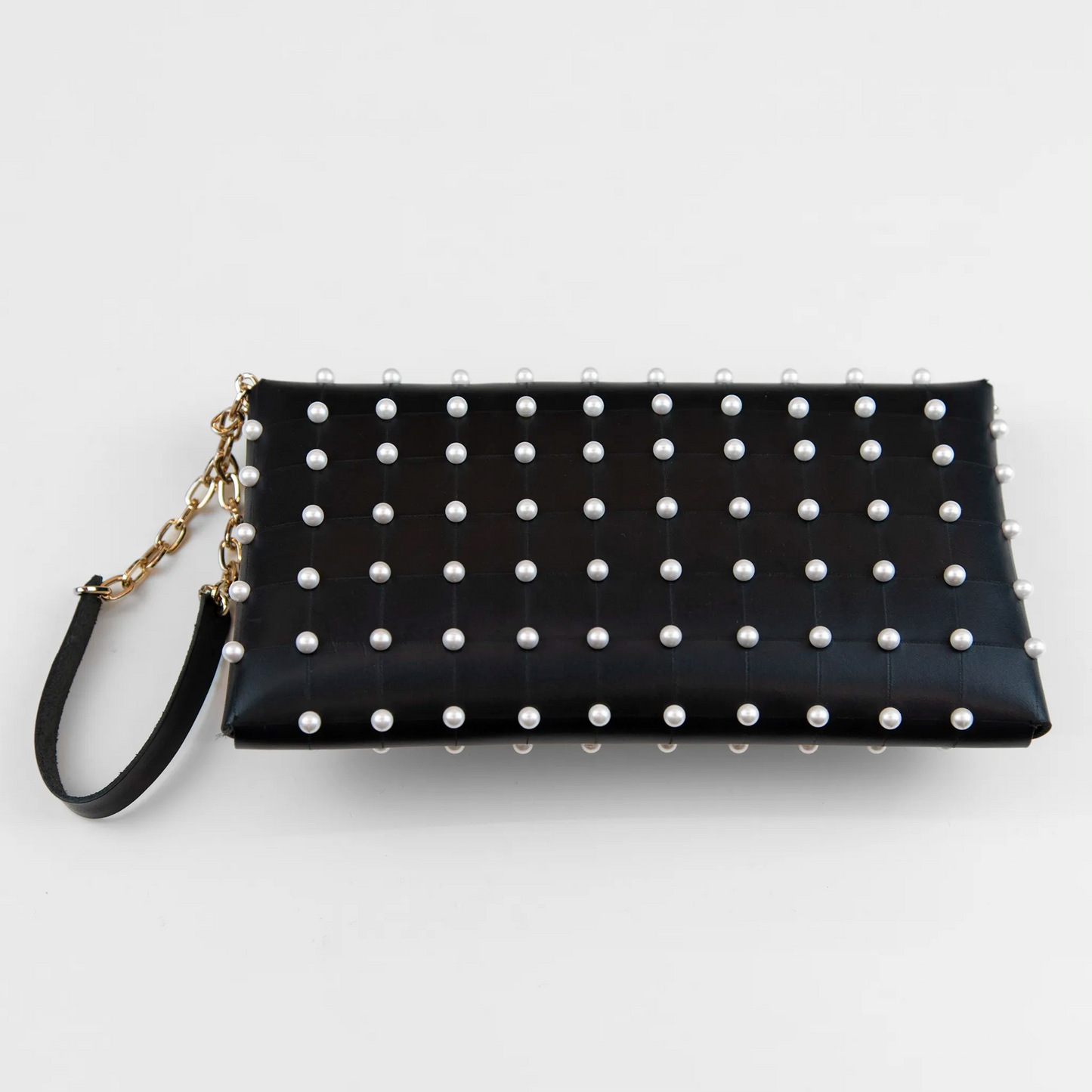 Clutch in pelle nera borchiata con chiusura a calamita, polsiera e tracolla per un pratico trasporto, Made in Italy, realizzata interamente a mano senza cuciture, secondo la tradizione degli antichi sellai Toscani, per robustezza e durata.