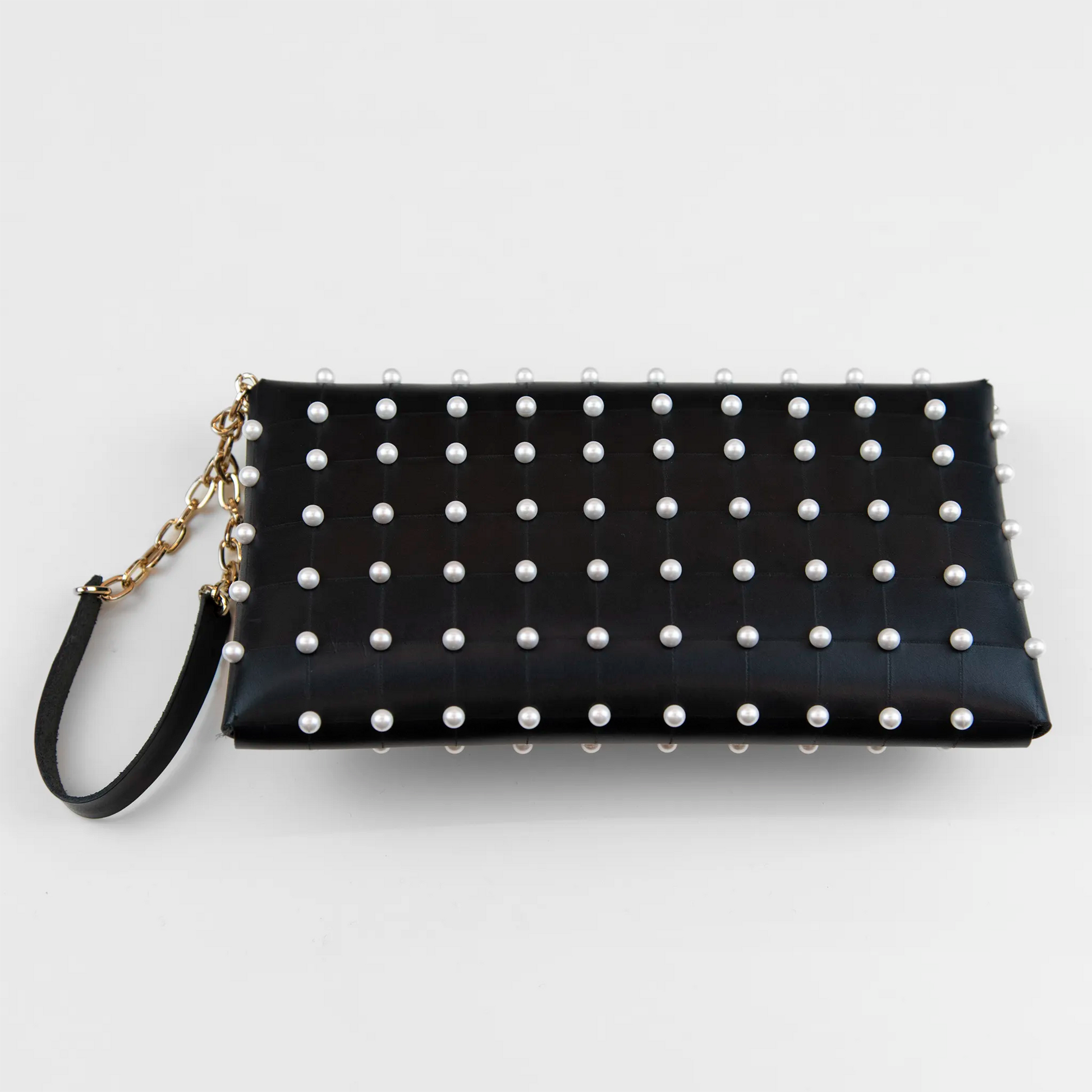 Clutch in pelle nera borchiata con chiusura a calamita, polsiera e tracolla per un pratico trasporto, Made in Italy, realizzata interamente a mano senza cuciture, secondo la tradizione degli antichi sellai Toscani, per robustezza e durata.