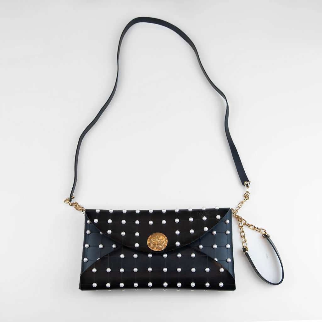 Clutch in pelle nera borchiata con chiusura a calamita, polsiera e tracolla per un pratico trasporto, Made in Italy, realizzata interamente a mano senza cuciture, secondo la tradizione degli antichi sellai Toscani, per robustezza e durata.