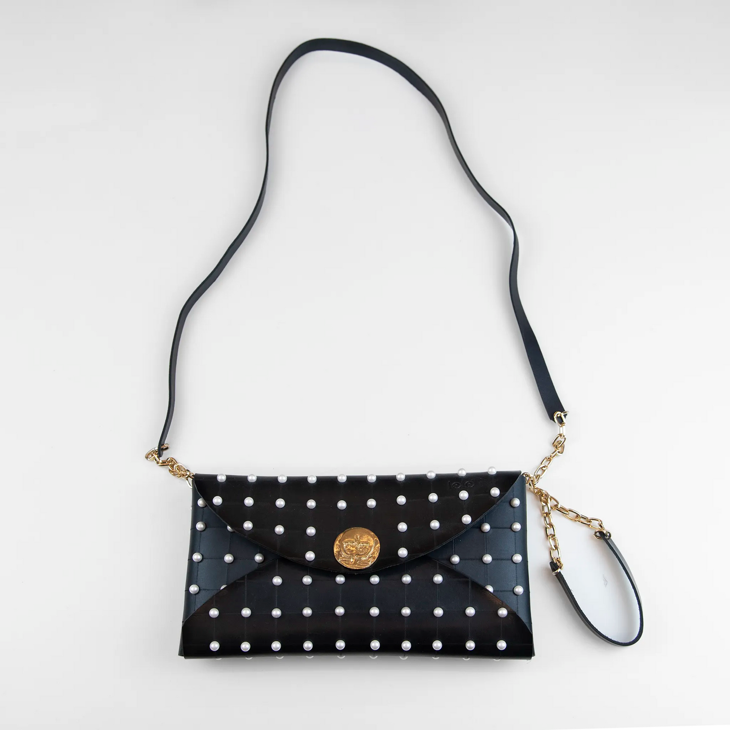 Clutch in pelle nera borchiata con chiusura a calamita, polsiera e tracolla per un pratico trasporto, Made in Italy, realizzata interamente a mano senza cuciture, secondo la tradizione degli antichi sellai Toscani, per robustezza e durata.