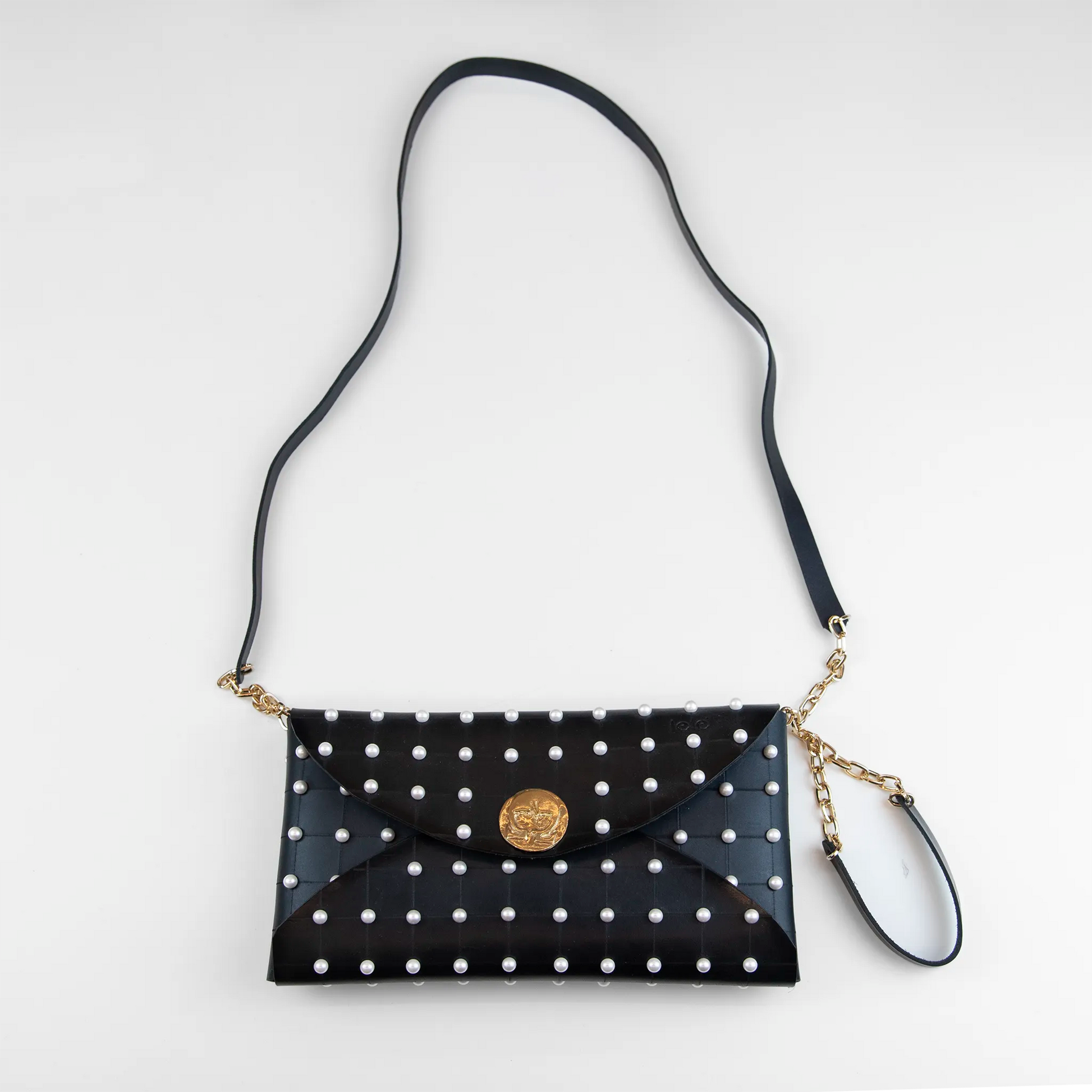 Clutch in pelle nera borchiata con chiusura a calamita, polsiera e tracolla per un pratico trasporto, Made in Italy, realizzata interamente a mano senza cuciture, secondo la tradizione degli antichi sellai Toscani, per robustezza e durata.