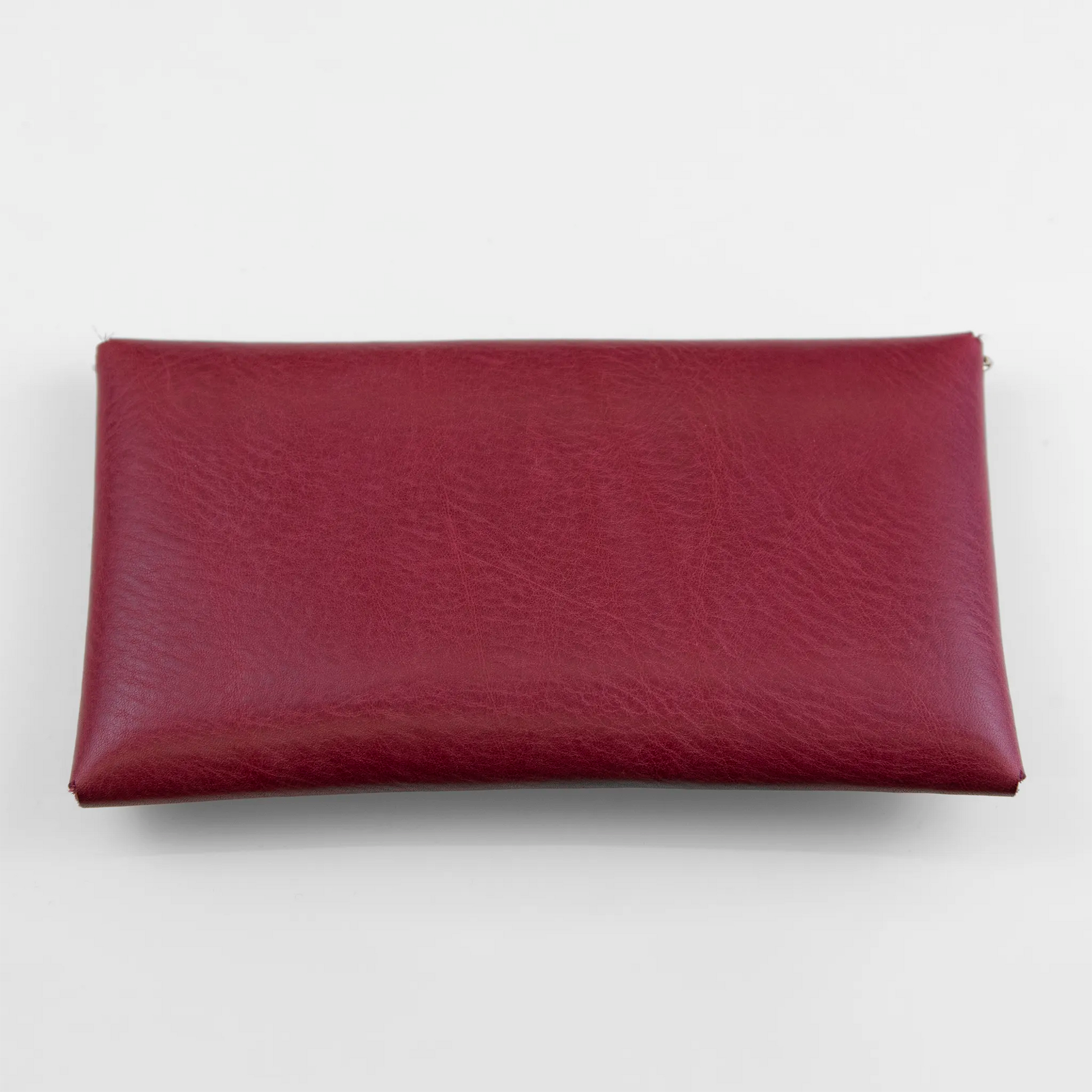 Clutch in pelle rossa con chiusura a calamita, polsiera e tracolla, Made in Italy, realizzata interamente a mano senza cuciture, secondo la tradizione degli antichi sellai Toscani, per una maggiore robustezza e durata nel tempo.