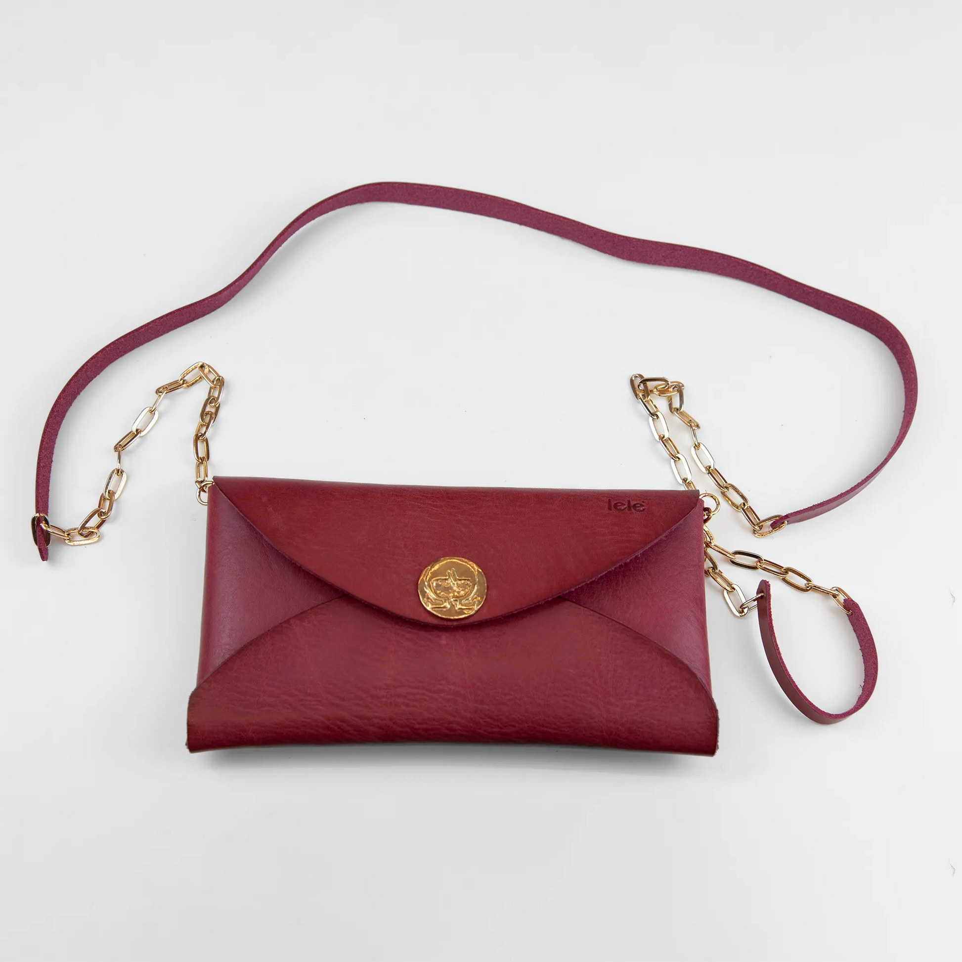 Clutch in pelle rossa con chiusura a calamita, polsiera e tracolla, Made in Italy, realizzata interamente a mano senza cuciture, secondo la tradizione degli antichi sellai Toscani, per una maggiore robustezza e durata nel tempo.